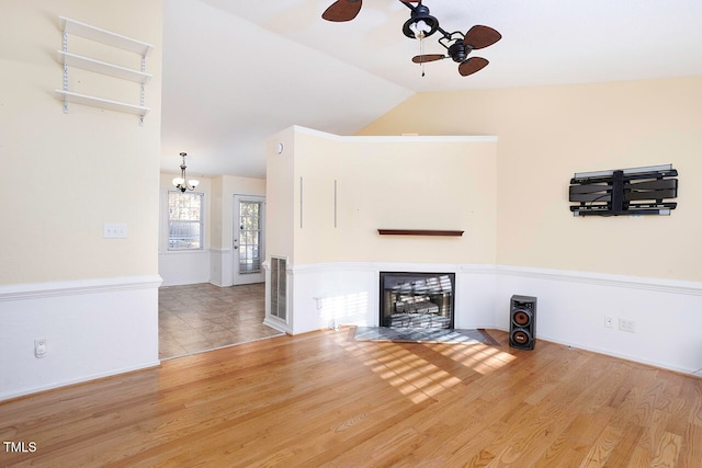 unfurnished living room featuring lofted ceiling, wood-type flooring, and ceiling fan with notable chandelier