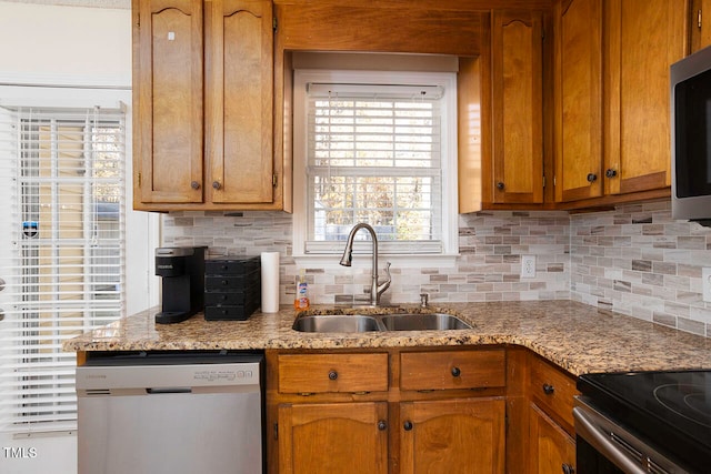 kitchen with light stone countertops, appliances with stainless steel finishes, backsplash, and sink