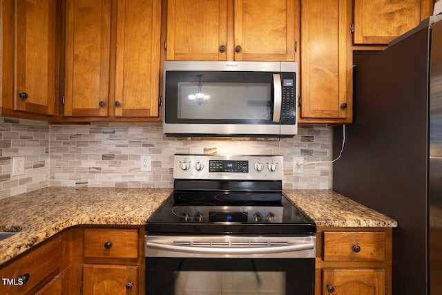 kitchen featuring decorative backsplash, light stone counters, and stainless steel appliances