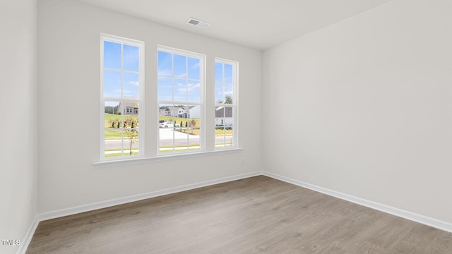 spare room featuring baseboards, visible vents, and wood finished floors