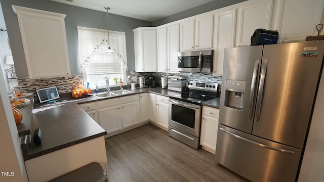 kitchen featuring dark wood-type flooring, white cabinets, sink, appliances with stainless steel finishes, and decorative light fixtures