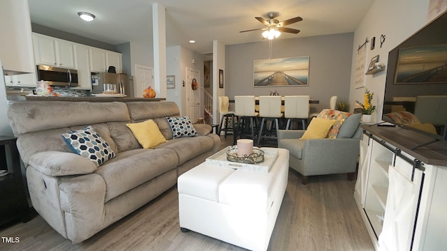 living room with light wood-type flooring and ceiling fan