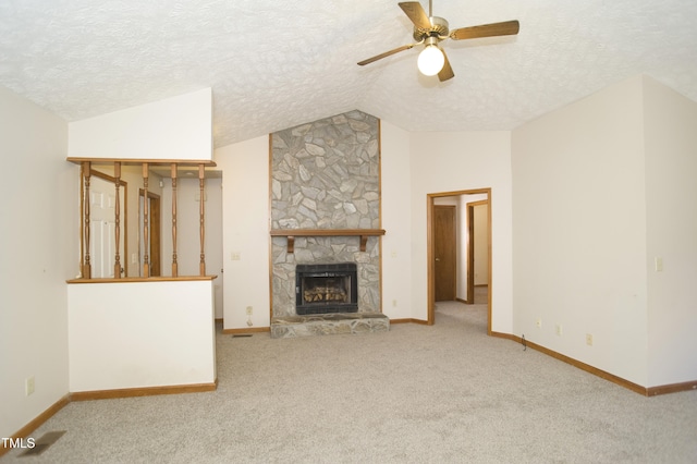 unfurnished living room with a textured ceiling, vaulted ceiling, ceiling fan, and a stone fireplace