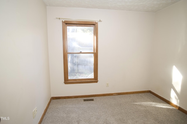 carpeted spare room with a textured ceiling