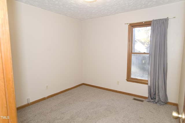 carpeted empty room featuring a textured ceiling