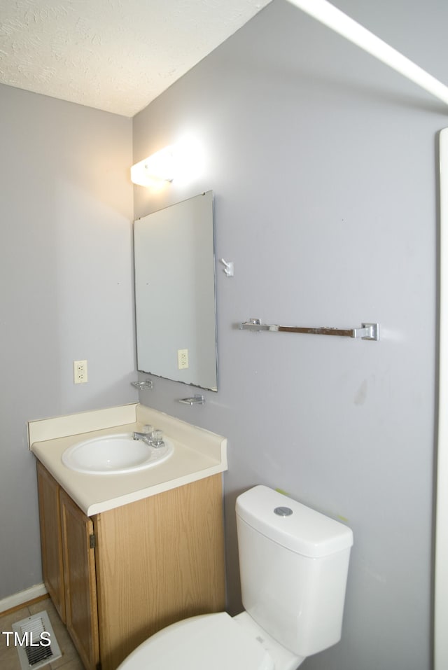 bathroom with a textured ceiling, vanity, and toilet