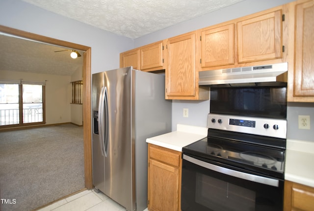 kitchen with light brown cabinets, a textured ceiling, stainless steel appliances, and light tile patterned flooring