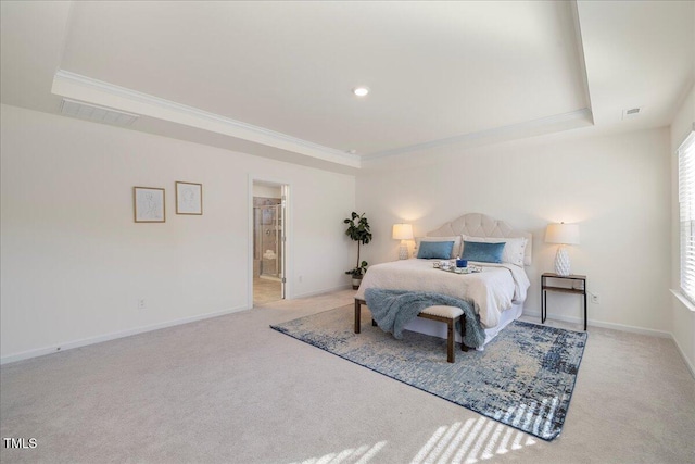 bedroom with a raised ceiling, connected bathroom, and multiple windows