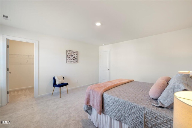 bedroom featuring a spacious closet, a closet, and light colored carpet