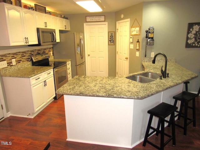 kitchen featuring white cabinets, appliances with stainless steel finishes, kitchen peninsula, and sink