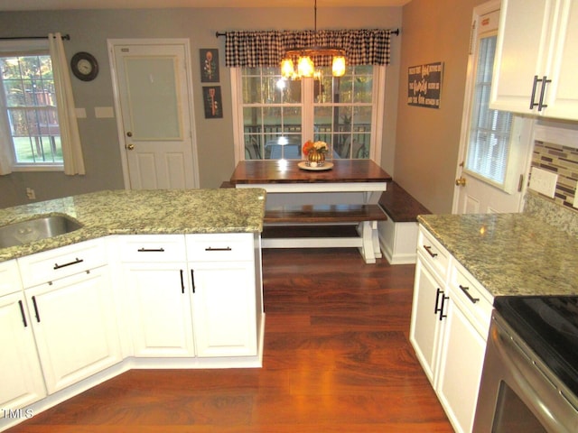 kitchen with light stone countertops, white cabinetry, hanging light fixtures, and dark hardwood / wood-style floors