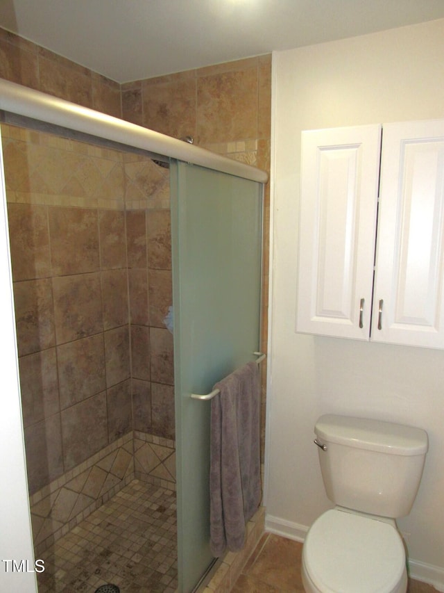 bathroom with tile patterned flooring, toilet, and an enclosed shower