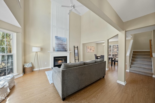 living room featuring ceiling fan, light hardwood / wood-style floors, and a high ceiling