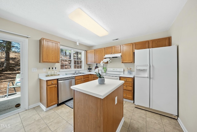 kitchen with light tile patterned flooring, sink, a textured ceiling, a kitchen island, and white appliances