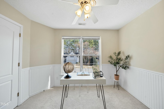 home office featuring ceiling fan, light carpet, and a textured ceiling