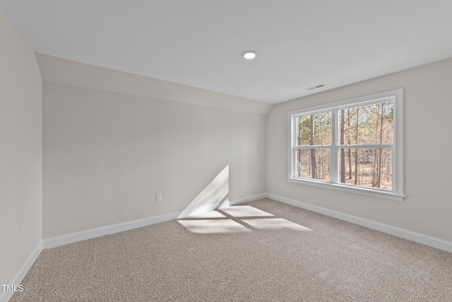 carpeted empty room featuring vaulted ceiling