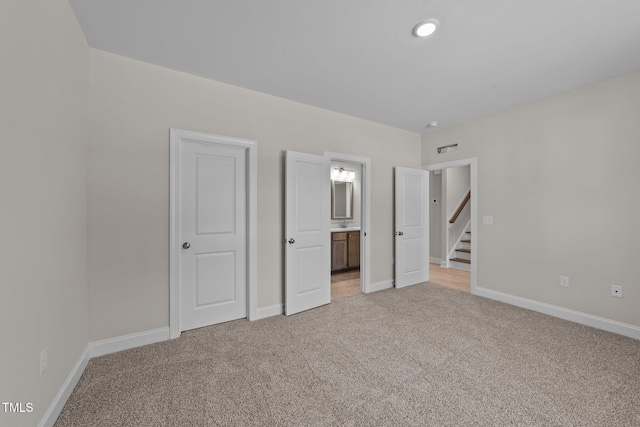 unfurnished bedroom featuring light colored carpet and connected bathroom