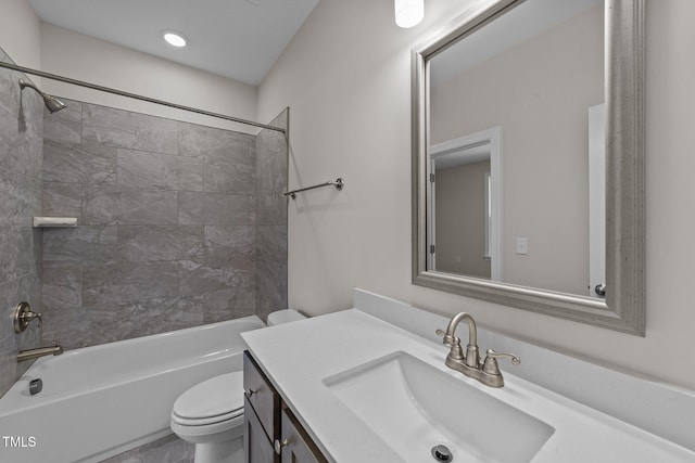 full bathroom featuring vanity, tiled shower / bath, and toilet