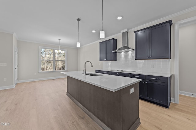 kitchen with decorative light fixtures, black electric cooktop, a kitchen island with sink, decorative backsplash, and wall chimney range hood