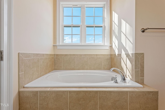 bathroom with a relaxing tiled tub and a healthy amount of sunlight