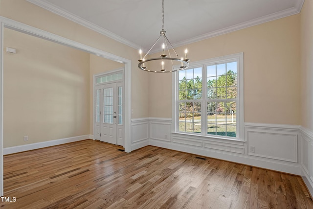 unfurnished dining area featuring ornamental molding, a chandelier, a wealth of natural light, and light wood-type flooring