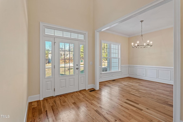 entryway featuring an inviting chandelier, ornamental molding, and wood-type flooring