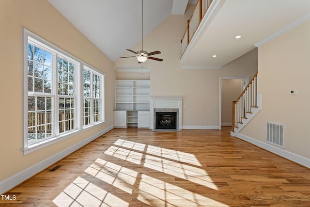 unfurnished living room featuring ceiling fan, a premium fireplace, light hardwood / wood-style flooring, and ornamental molding