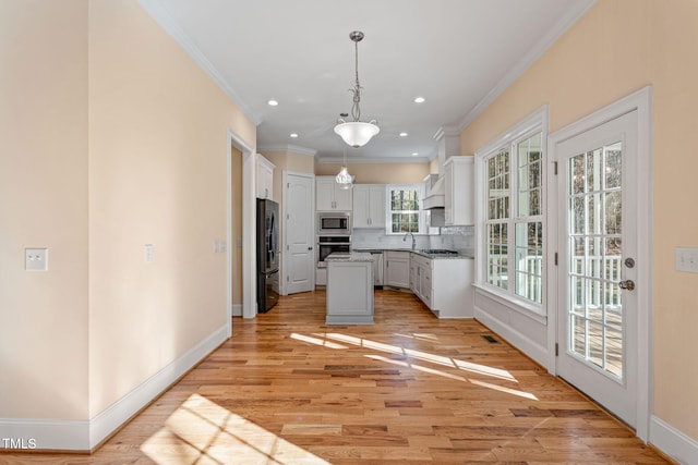 kitchen with appliances with stainless steel finishes, a center island, pendant lighting, white cabinets, and tasteful backsplash