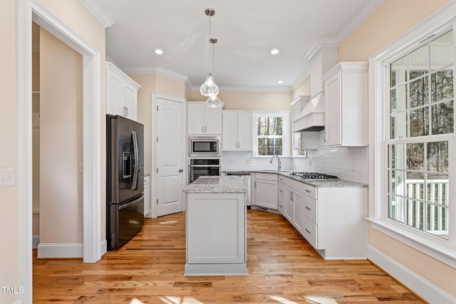 kitchen featuring hanging light fixtures, a center island, stainless steel appliances, light hardwood / wood-style floors, and white cabinetry