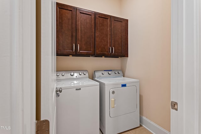 washroom with washing machine and dryer, cabinets, and light tile patterned flooring