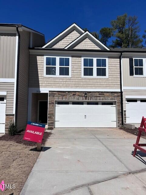 view of front facade featuring stone siding, concrete driveway, and a garage