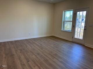 empty room featuring dark wood-style floors and baseboards