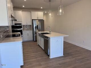 kitchen with stainless steel appliances, backsplash, dark wood-type flooring, white cabinetry, and a sink