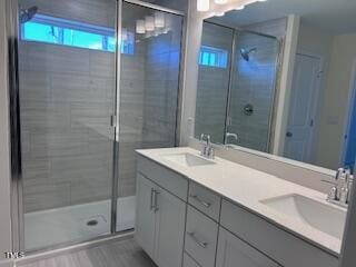 full bathroom with a stall shower, a sink, and double vanity