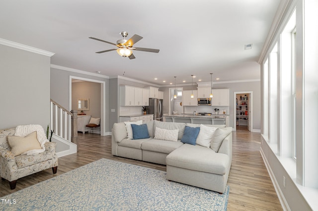 living room featuring a healthy amount of sunlight, crown molding, and light hardwood / wood-style flooring