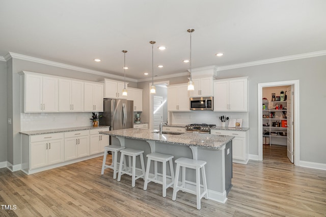 kitchen with appliances with stainless steel finishes, light hardwood / wood-style floors, white cabinetry, and sink