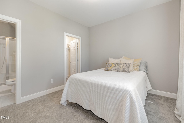 bedroom featuring light carpet, a walk in closet, ensuite bathroom, and a closet