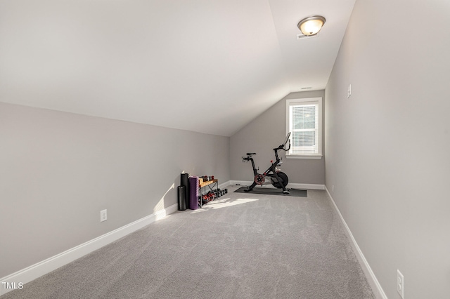 exercise area featuring light colored carpet and vaulted ceiling