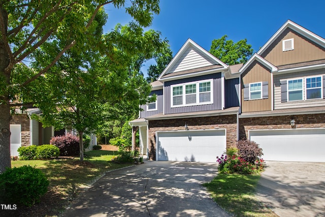 view of property featuring an attached garage, board and batten siding, driveway, and stone siding