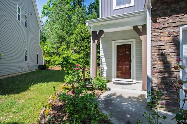 entrance to property featuring board and batten siding, a yard, and covered porch