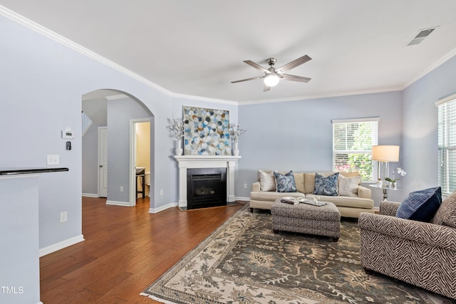 living room featuring visible vents, ornamental molding, hardwood / wood-style floors, ceiling fan, and arched walkways