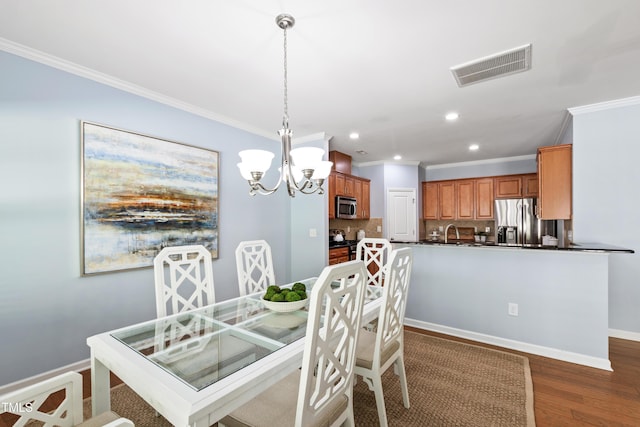 dining area featuring a notable chandelier, visible vents, ornamental molding, and wood finished floors