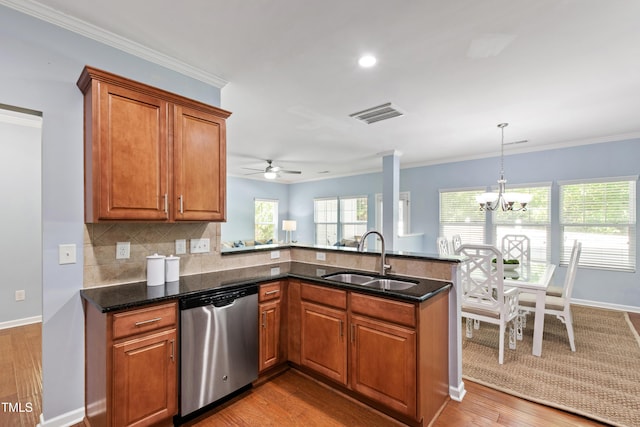kitchen featuring brown cabinetry, visible vents, stainless steel dishwasher, a sink, and a peninsula