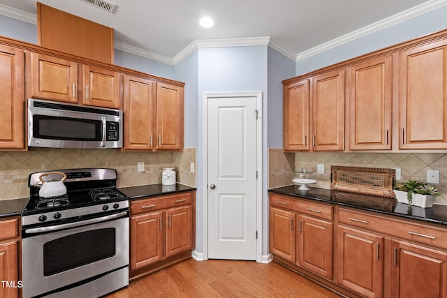 kitchen featuring light wood-style floors, crown molding, brown cabinetry, and stainless steel appliances