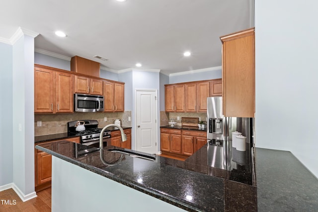kitchen with a sink, backsplash, stainless steel appliances, and brown cabinets