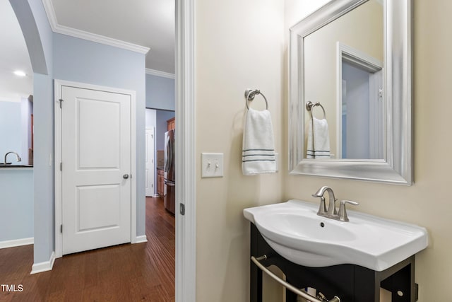 bathroom featuring crown molding, baseboards, wood finished floors, and vanity
