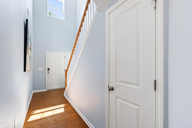 interior space with stairs, baseboards, wood finished floors, and a towering ceiling