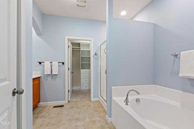 full bath featuring a walk in closet, a garden tub, visible vents, a shower stall, and vanity