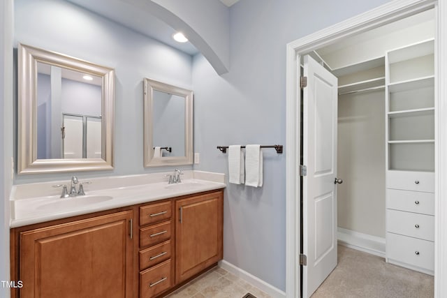 bathroom with double vanity, baseboards, and a sink
