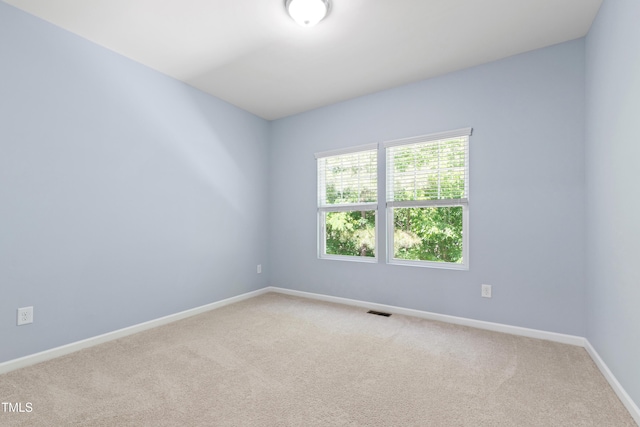 unfurnished room featuring baseboards, light carpet, and visible vents
